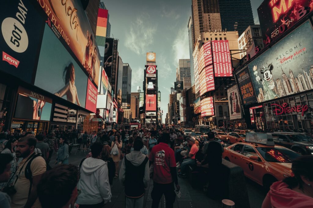 A bustling view of Times Square, New York City, filled with lights and people at sunset.
